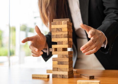 businesswoman holds her hand on a wooden block with a weak base. It is like a business risk mitigation strategy. and project management the best of the business
