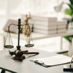 law firm courtroom Law books, computer and scales of justice on table in lawyer office